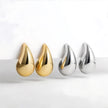 Two pairs of gold and silver teardrop-shaped earrings on a white background