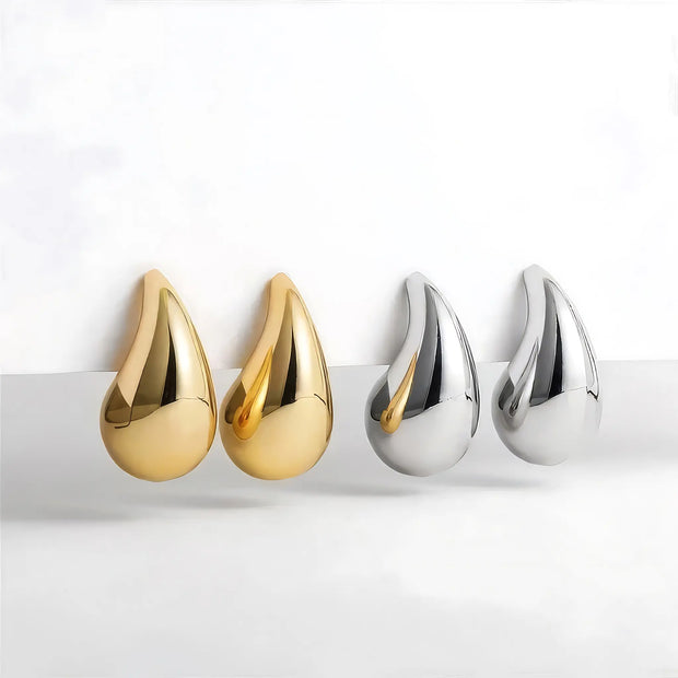 Two pairs of gold and silver teardrop-shaped earrings on a white background