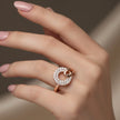 Rose gold ring with diamonds on a hand against a neutral background