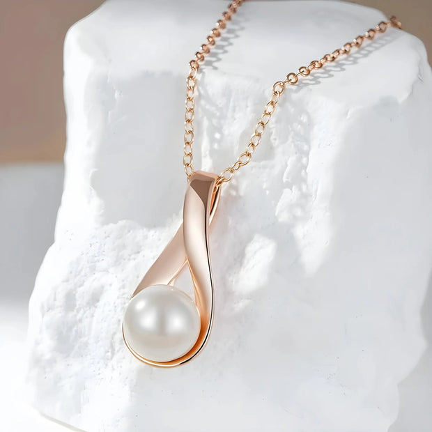 Rose gold necklace with a pearl pendant on a white rock.