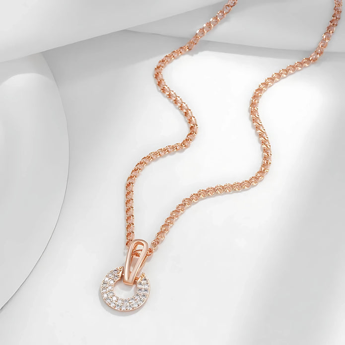 Rose gold necklace with a circular pendant on a light gray background