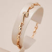 Rose gold bracelet on a white stand with a soft beige background