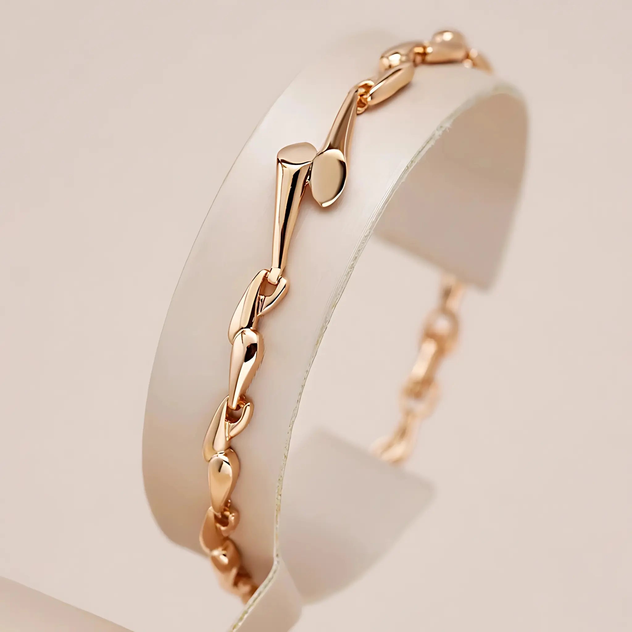 Rose gold bracelet on a white stand with a soft beige background