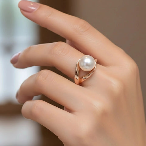 Hand wearing a rose gold pearl ring with a blurred background