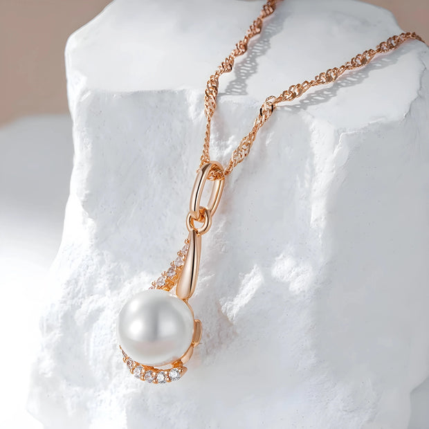 Pearl necklace with rose gold chain on a textured white surface